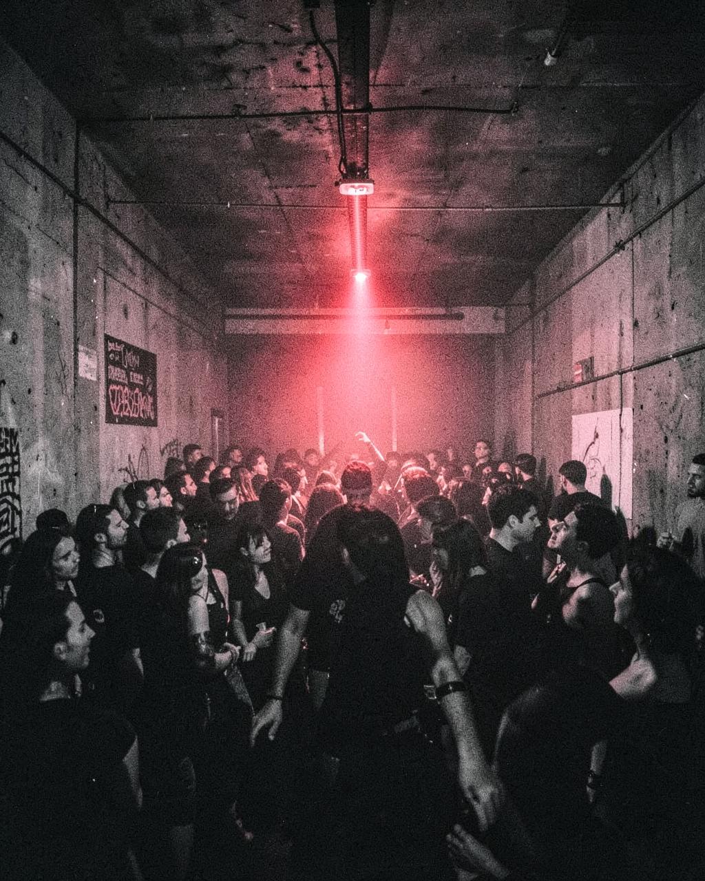 Rave em galpão de concreto com luz vermelha